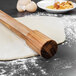 A Fox Run acacia wood rolling pin on dough.