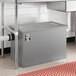 A gray metal Regency grease trap with a metal lid over a sink drain.