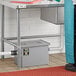 A person standing next to a Regency grease trap in a school kitchen.