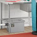 A person standing next to a Regency grease trap under a sink.