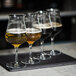 A tray with four Luigi Bormioli beer tester glasses filled with beer.