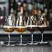 A group of Luigi Bormioli Birrateque beer testers filled with different types of beer on a table in a brewery tasting room.