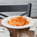 An Ivory (American White) china soup dish filled with spaghetti and meatballs on a table.