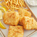 A plate of fried fish and fries with a lemon wedge.