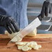 A person using a Dexter-Russell chef knife to cut vegetables on a counter.
