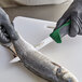 A person in gloves using a Dexter-Russell narrow flexible boning knife to cut fish.