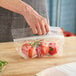 A hand holding a clear plastic bag of tomatoes.