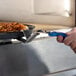 A person using a GI Metal stainless steel pan gripper to lift a deep pizza pan off a counter.