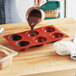 A woman pouring chocolate into a Silikomart silicone baking mold.