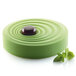 A green cake with a brown object on top in a Silikomart Vague silicone baking mold.