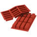 A close-up of a red Silikomart silicone baking mold with 12 compartments.