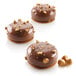Three Silikomart STONE 85 chocolate desserts with nuts on top displayed on a table.