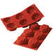 A close up of a red Silikomart sunflower silicone mold with six flower-shaped cavities.