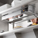 A woman in a kitchen using a ServIt strip warmer over plates of food.