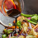 A hand pouring Lee Kum Kee Mushroom Flavored Dark Soy Sauce into a bowl of food.