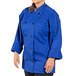 A woman wearing a royal blue Uncommon Chef long sleeve chef coat.