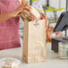 A woman holding a sandwich in a Duro brown paper bag.