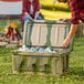 A man opens a CaterGator camouflage cooler on a table in an outdoor setting.