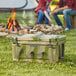 A man and woman sitting on a picnic blanket next to a CaterGator camouflage cooler.