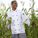 a man in a white coat standing in a corn field
