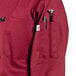A burgundy Uncommon Chef long sleeve chef coat with a pocket and pen on the sleeve.