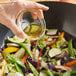 A person pouring Lee Kum Kee sesame flavored seasoning oil into a bowl of salad.