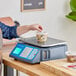 A person weighing food in a plastic container on a blue and white AvaWeigh scale.