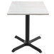 A white table with a white ash wood top and black cross base.