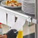A person using a Vollrath aluminum wall mounted ticket holder to hold a receipt.