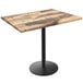 A Holland Bar Stool rustic wood laminate table top on a round black metal base.