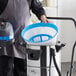 A man using a Lavex stainless steel wet/dry vacuum in a professional kitchen.