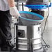 A man using a Lavex stainless steel wet/dry vacuum to clean a floor in a professional kitchen.