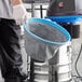 A person using a Lavex stainless steel wet/dry vacuum to clean up a mess.