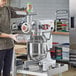 A man using an Avantco commercial stand mixer with a meat grinder attachment.