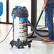 A man using a Lavex stainless steel wet/dry vacuum in a professional kitchen.