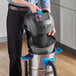 A man using a Lavex wet/dry vacuum to clean a professional kitchen floor.