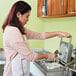 A woman pouring batter into a Hatco commercial waffle maker.