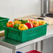 Two green Orbis agricultural crates filled with bell peppers on a green counter.