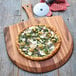 A pizza on a Fox Run acacia wood pizza peel on a table.