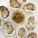 A variety pack of Rappahannock live oysters on ice with a small bowl of dipping sauce.