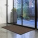 A brown Lavex parquet entrance mat on the floor in front of a glass door.