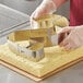 A person using an Ateco stainless steel number 2 cake cutter to cut a cake.