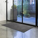 A Lavex charcoal olefin doormat with leaves in the background.