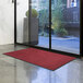 A red Lavex Olefin entrance mat rolled out on the floor.