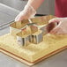 A person using an Ateco stainless steel number 4 cutter to cut dough.