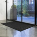 A black Lavex Waffle entrance mat on a floor.