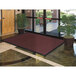 A large red Lavex Chevron Rib entrance mat unrolled in front of a glass door.
