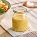 A small round glass jar filled with a light-colored dressing, labeled as a 6 oz. American Metalcraft RGJ6 jar.