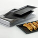 A black rectangular Solia slate tray with food on it.