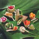 A group of small bamboo leaf bowls filled with vegetables on a bamboo leaf.